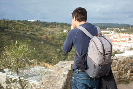 Man male photographer photographing a city and landscape from castle wall in Mertola, Portugal