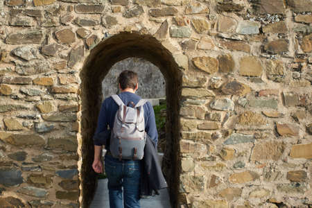 Man backpacker tourist traveler walking in castle wall entrance in Mertola Alentejo, Portugal