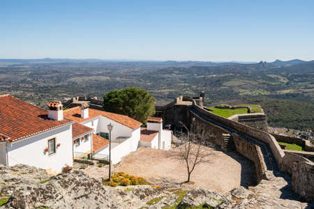 View of Marvao village with beautiful houses and church with rocky landscape mountains behindの写真素材