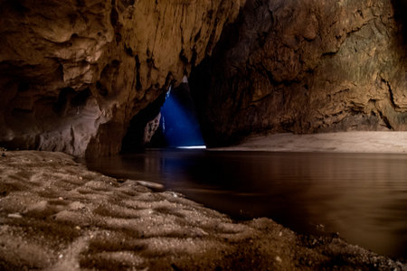 Mysterious Cave Interior with River and Beam of Lightの写真素材