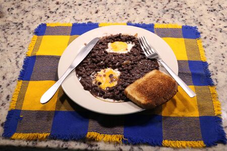 fried eggs with beans and a colorful tableclothの写真素材