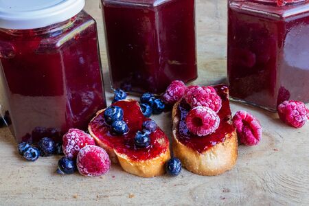 Homemade berries mermelade in jars and served in toastの写真素材