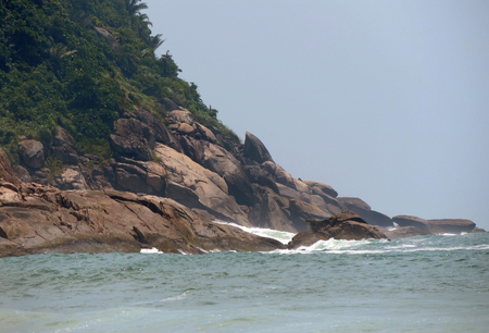 Rock formations at the base of a mountain by the seaの写真素材