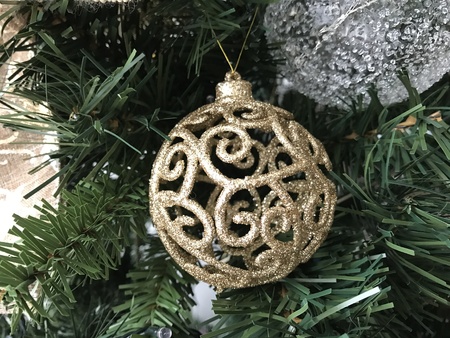 Golden ornament ball in the middle of the leaves of a Christmas treeの写真素材