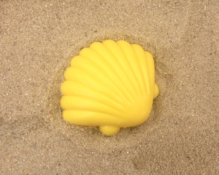A yellow plastic shell on the sand