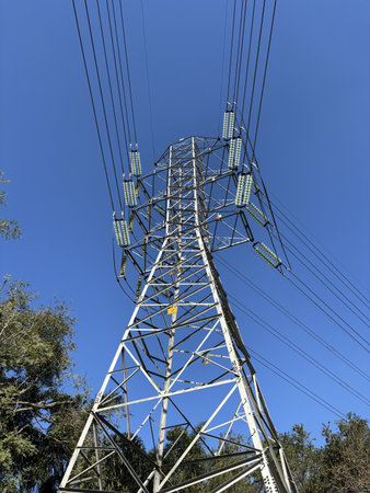 High Voltage tower framed by the blue sky - Yellow warning translation (Danger, Don't Climb)