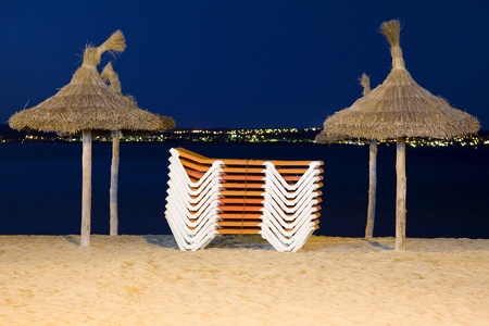 Night view of a beach with sunshades and grouped deckchairs as a concept of の写真素材