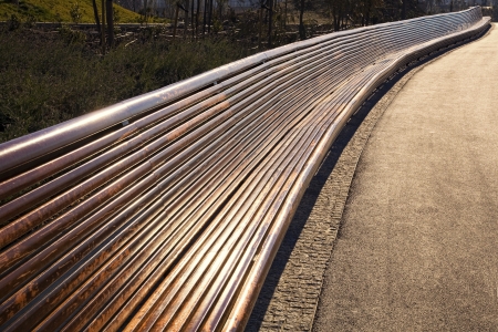 Very long empty wooden bench in a park at duskの写真素材
