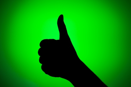 Silhouette of hand with thumb up on a green background