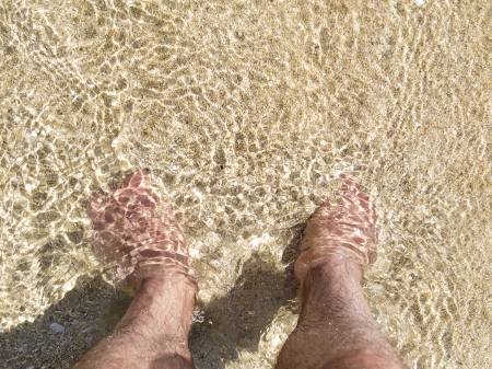 Feet in the sand in shallow water with copy spaceの写真素材