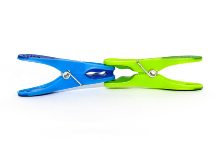 Green clothespin clamping blue clothespin on a white backgroundの写真素材