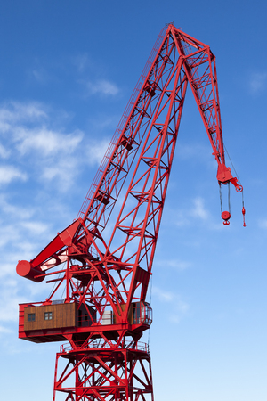 Old red harbour crane agains a cloudy blue skyの写真素材