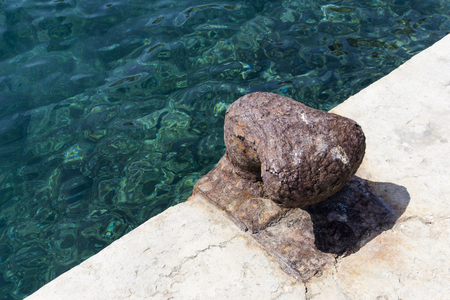 Rusty iron mooring bollard close to the seaの写真素材