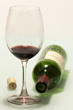 Cup with red wine, cork and empty bottleの写真素材