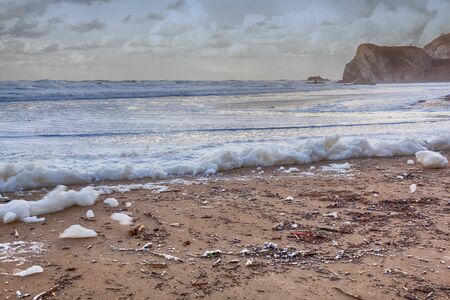 Close view of foam on a polluted beachの写真素材