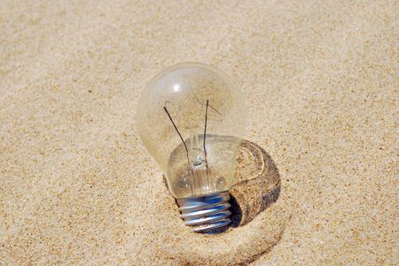 concept of a lightbulb on sand (environment issue)の写真素材