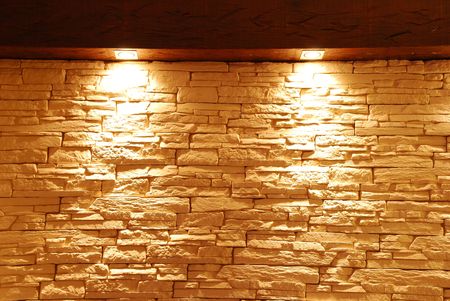 grey and unshaped stone wall with spot lightsの写真素材