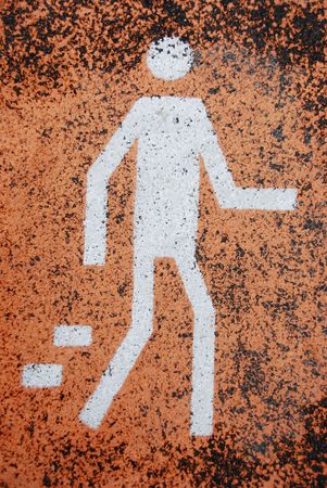 white pedestrian road sign painted on orange asphalt surfaceの写真素材