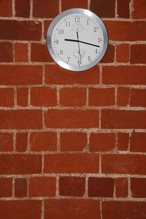 grey and white wall clock on a residential brick flatの写真素材