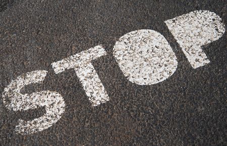 stop sign painted on a asphalt road surfaceの写真素材