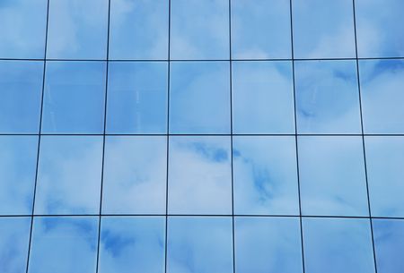 modern office building with glass pattern with clouds reflectedの写真素材
