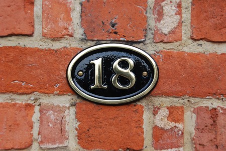 white metallic number (18) hanging a brick wallの写真素材