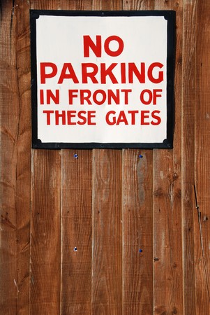 no parking in front of these gates vintage sign at a wooden fence background
