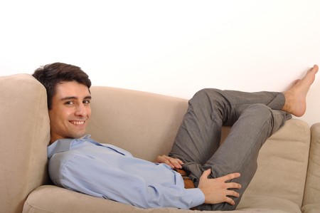 attractive young man lying and relaxing on the couch (isolated on white background)の写真素材
