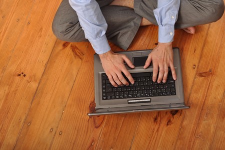 man with laptop computer sitting on the floor at homeの写真素材
