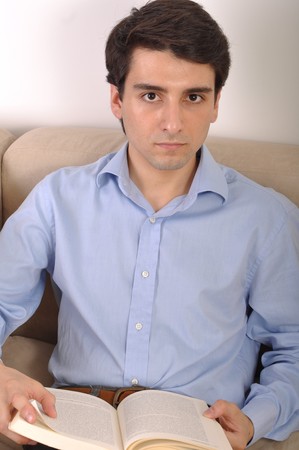 attractive young man reading a business book on the couchの写真素材