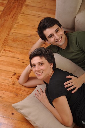 lovely friendship between sister and brother lying and relaxing on the floor next to couchの写真素材