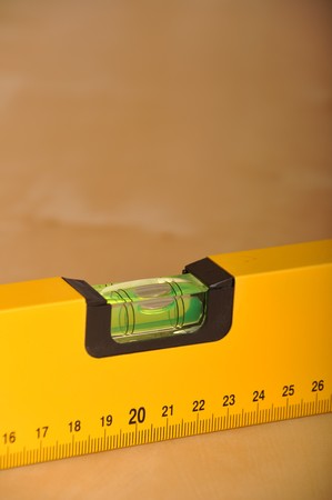 yellow construction level on a brown wooden backgroundの写真素材