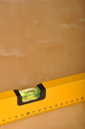 yellow construction level on a brown wooden background