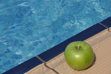 green apple at the pool side as a diet concept (healthy food and exercise)の写真素材