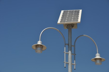 street lamp post with solar panel energy (against blue sky background)の写真素材