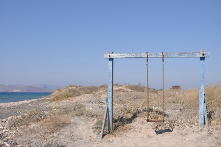 old and rusty swing on a Greek beachの写真素材