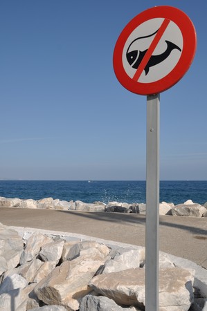 no fishing allowed sign on stone pier (ocean and sky background)の写真素材