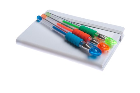 grey notebook diary or agenda and colored pens lying on the top (isolated on white background)の写真素材