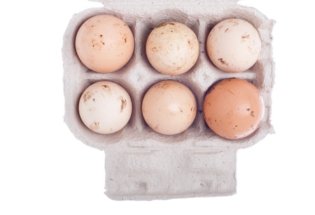 six dirty eggs in a carton box isolated on white backgroundの写真素材