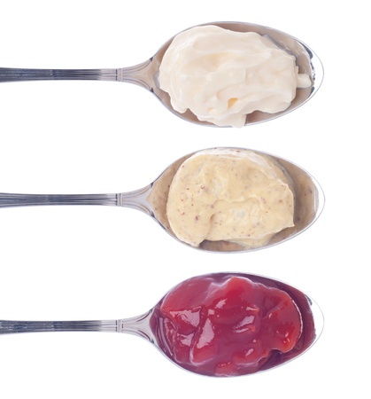 mayonnaise, mustard and ketchup on silver spoons isolated on white backgroundの写真素材