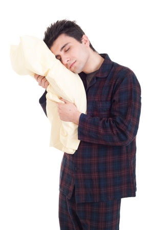 sleepy young man in pajamas holding pillow isolated on white backgroundの写真素材