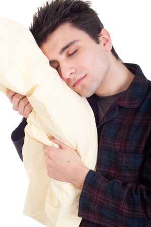 sleepy young man in pajamas holding pillow isolated on white backgroundの写真素材