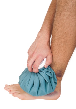 young male icing a sprained ankle with ice pack (isolated on white background)の写真素材