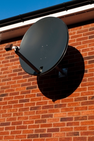 black satellite dish attached to brick wall  residential house, copy-space available の写真素材