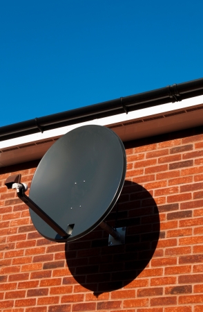black satellite dish attached to brick wall  residential house, copy-space available の写真素材