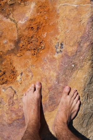 young man barefoot on rocky beach in Algarve, Portugalの写真素材