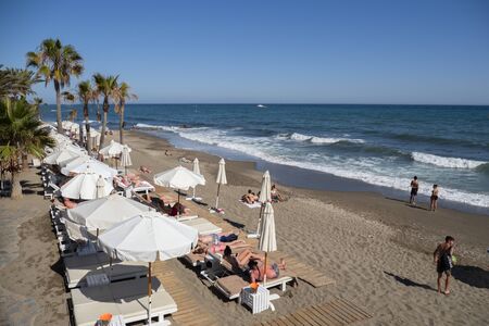 MARBELLA, SPAIN - JUNE 21, 2019: Playa de Venus in Marbella, MÃ¡laga, Spain. View of umbrellas and sunbeds on the sand with the buildings of the promenade in the backgroundのeditorial素材