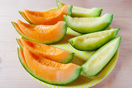 Fresh sliced melon with plate on wooden background at melon farm in Furano, Hokkaido, Japan. Juicy summer sweet fruit.の写真素材
