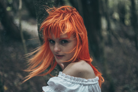 Young woman in white dress in dark forestの写真素材