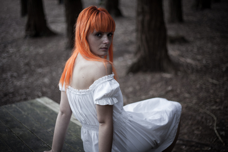 Young woman in white dress in dark forestの写真素材